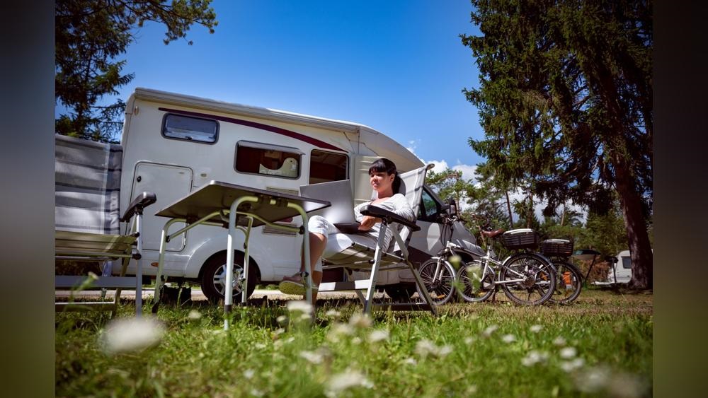 Foto: Wohnmobil mit einer Person im Campingstühl davor 