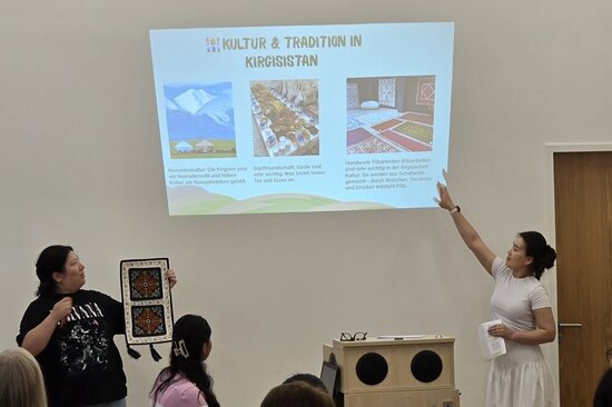 Foto: Frauen vor einer Vortragsfolie an der Wand