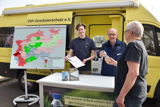 Foto: Drei Männer vor einem gelben Auto mit einer Karte