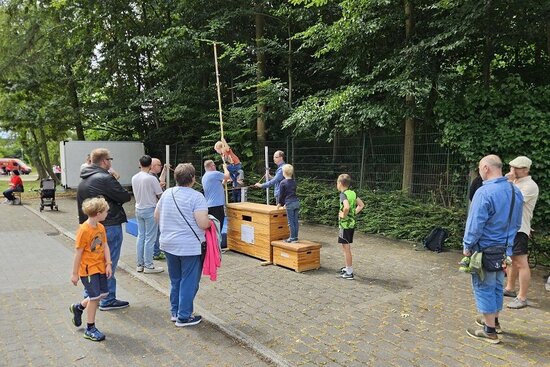 Foto: Menschengruppe und Holzböcke aus einer Turnhalle