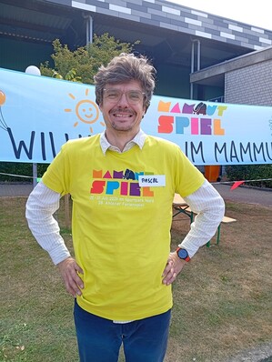 Foto: Person mit einem T-Shirt der Mammutspiele vor einem Banner