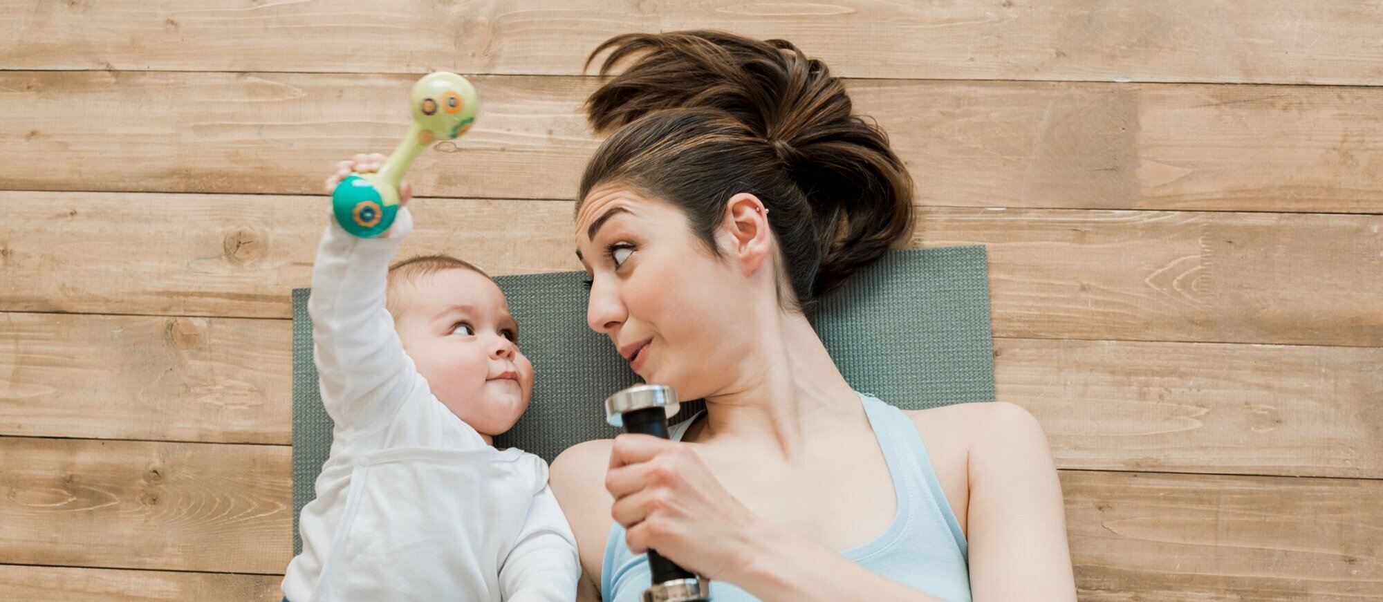Foto: Mutter liegt mit ihrem Baby auf einer Yogamatte