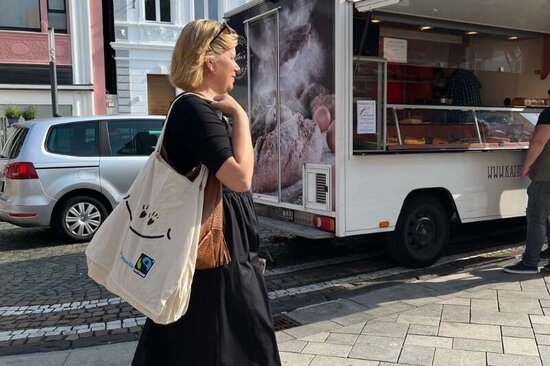 Frau mit Jutebeutel über der Schulter auf dem Weg zum Wochenmarkt
