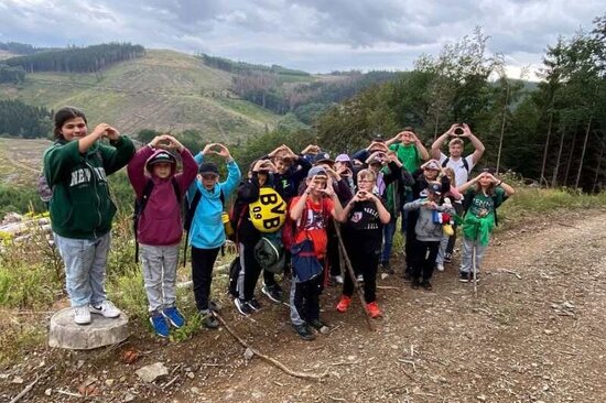 Gruppenbild auf kleinem Berg auf Waldboden mit Bergen im Hintergrund