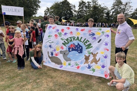 Foto: BM Harmann mit Kindern die ein Australien-Banner halten