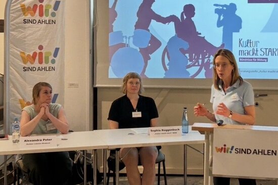 Foto: Drei Personen vor einer Präsentation mit einem Beamer
