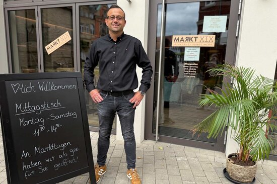 Ein Herr steht vor Restaurant mit Schild