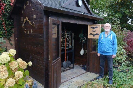 Foto: ein Mann vor einer Holzhütte mit Fledermausabbildungen